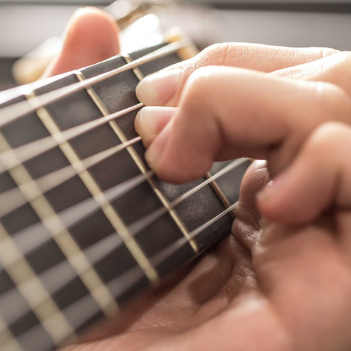 Greifhand am Griffbrett einer Gitarre
