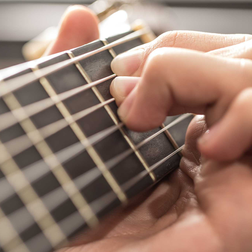 Greifhand am Griffbrett einer Gitarre