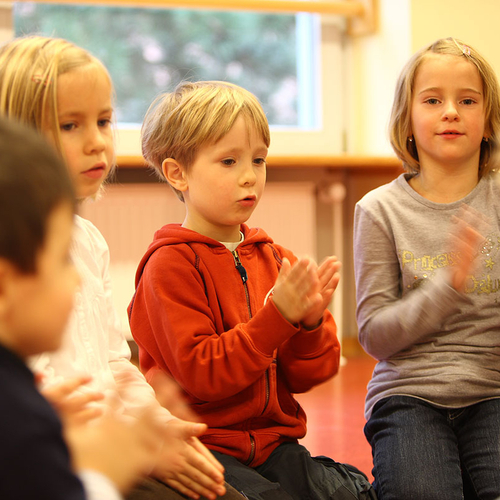 Kinder singen und klatschen im Stuhlkreis